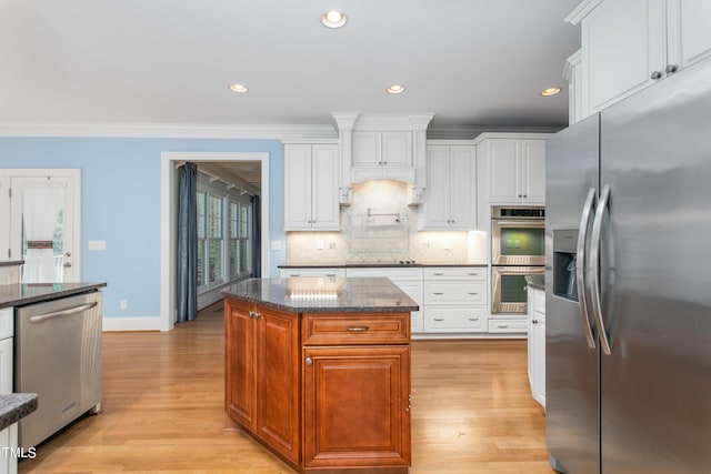 kitchen with light hardwood / wood-style floors, white cabinets, stainless steel appliances, and a kitchen island