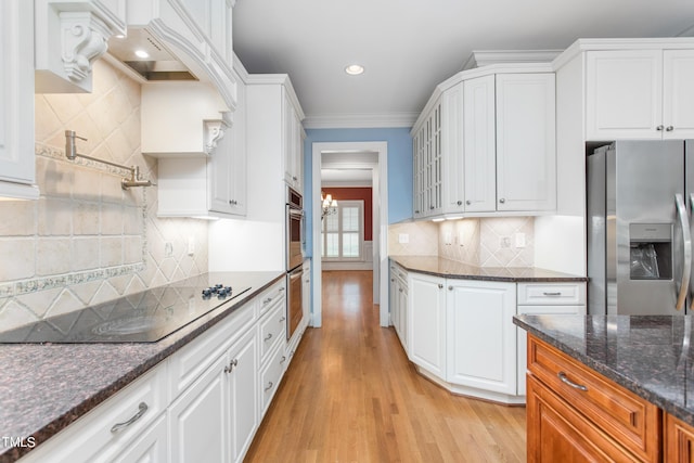 kitchen featuring crown molding, appliances with stainless steel finishes, light wood-type flooring, white cabinetry, and dark stone counters