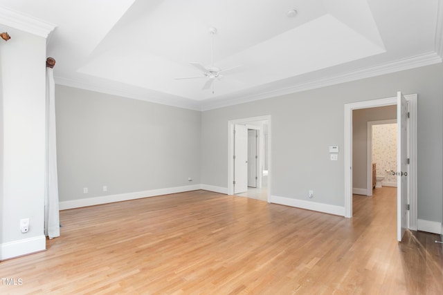 unfurnished room with light wood-type flooring, ceiling fan, a raised ceiling, and crown molding