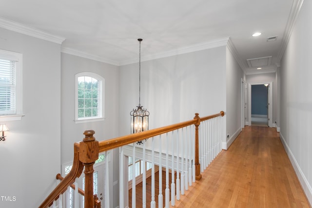 corridor featuring light hardwood / wood-style floors, ornamental molding, and an inviting chandelier