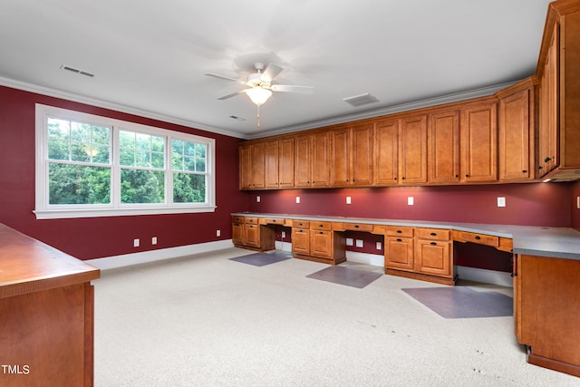 office featuring ceiling fan, light carpet, crown molding, and built in desk