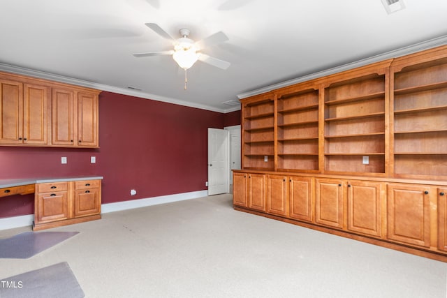 interior space with built in desk, ceiling fan, crown molding, and light carpet