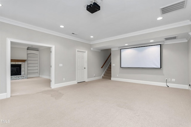 carpeted cinema with built in shelves, a brick fireplace, and crown molding