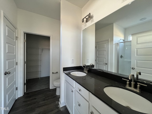 bathroom featuring hardwood / wood-style flooring, vanity, toilet, and a shower with door