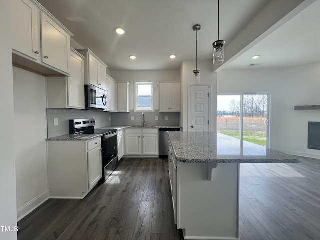 kitchen featuring tasteful backsplash, a kitchen island, dark wood finished floors, stainless steel appliances, and white cabinetry