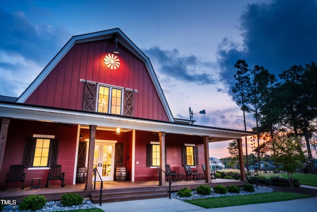 view of front of property with an outbuilding, french doors, covered porch, board and batten siding, and a barn