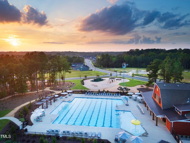 pool at dusk with a patio and a community pool