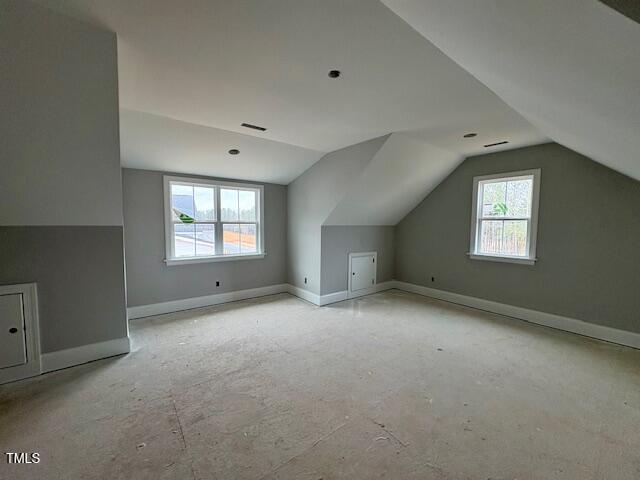 bonus room with lofted ceiling and baseboards