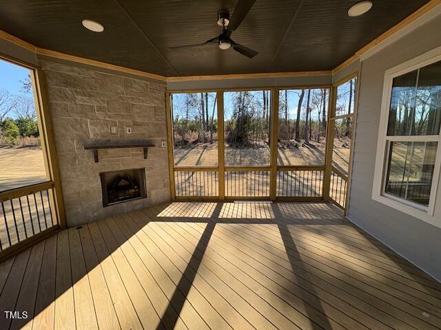 unfurnished sunroom with wooden ceiling, a fireplace, and a ceiling fan