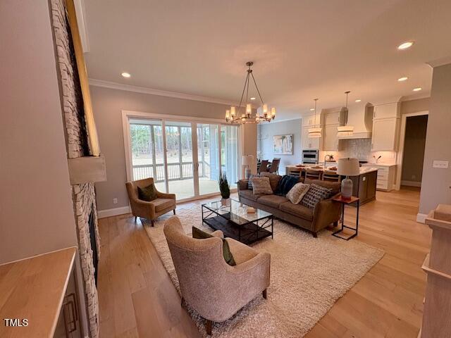 living area featuring recessed lighting, an inviting chandelier, ornamental molding, light wood-type flooring, and baseboards