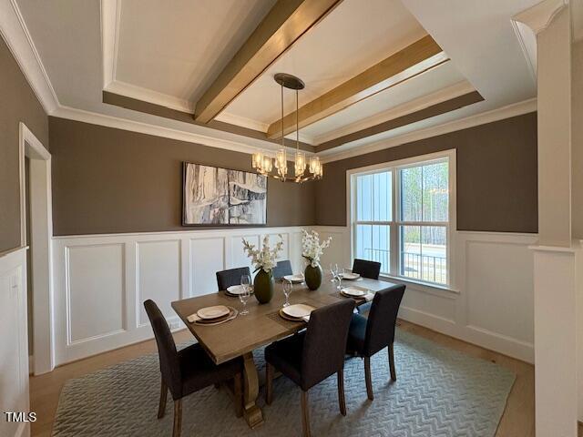 dining area with beam ceiling, a wainscoted wall, and crown molding