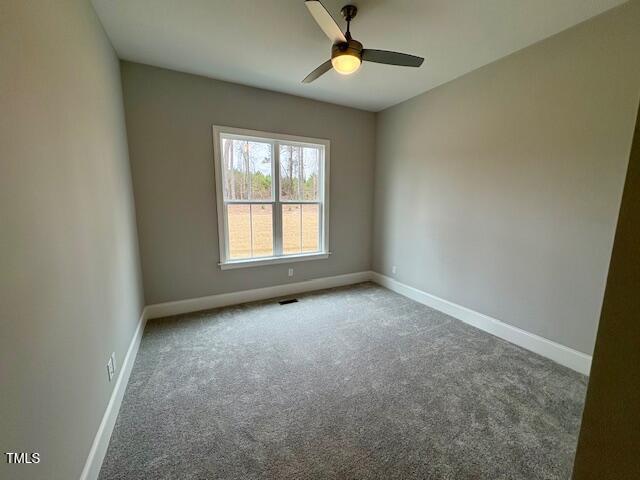 carpeted empty room featuring ceiling fan, visible vents, and baseboards