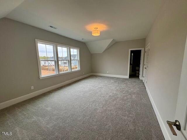 additional living space featuring lofted ceiling, baseboards, visible vents, and carpet flooring