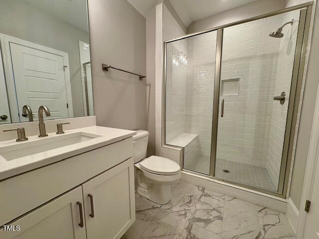 bathroom featuring marble finish floor, a shower stall, toilet, and vanity