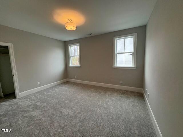 unfurnished bedroom with carpet flooring, visible vents, and baseboards