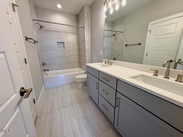 bathroom with a sink, bathing tub / shower combination, toilet, and double vanity