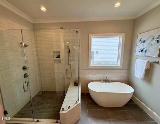 bathroom with a soaking tub, tile patterned flooring, ornamental molding, and a shower stall