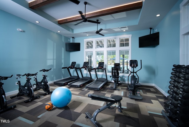 exercise room with a raised ceiling, ceiling fan, and carpet flooring