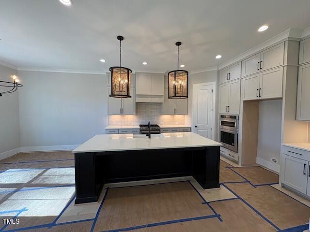 kitchen featuring sink, crown molding, a kitchen island with sink, tasteful backsplash, and stainless steel double oven