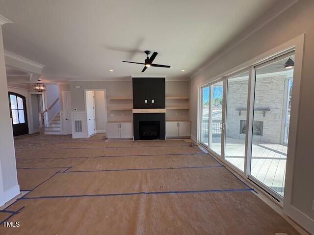 unfurnished living room with crown molding, a large fireplace, and a wealth of natural light