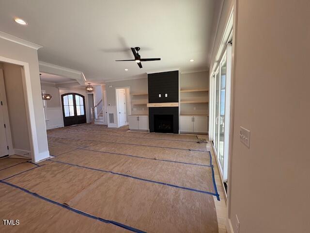 unfurnished living room featuring crown molding, a fireplace, and ceiling fan