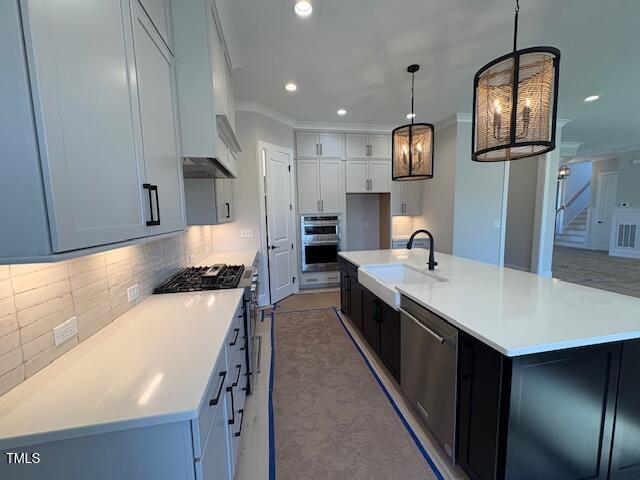 kitchen with sink, hanging light fixtures, appliances with stainless steel finishes, a large island, and backsplash