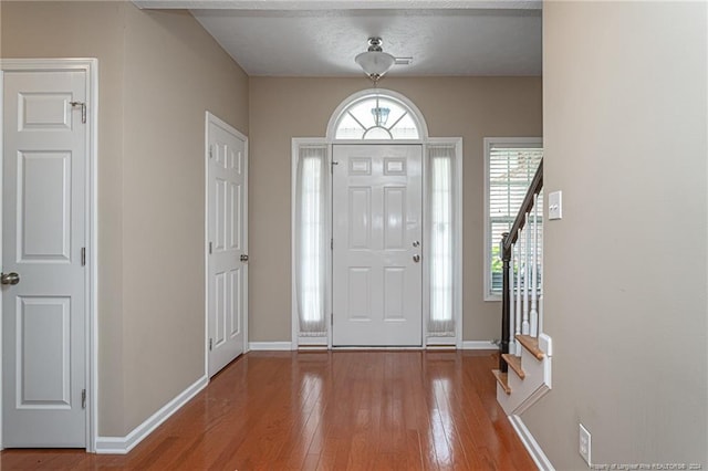 entryway featuring hardwood / wood-style floors, stairs, and baseboards