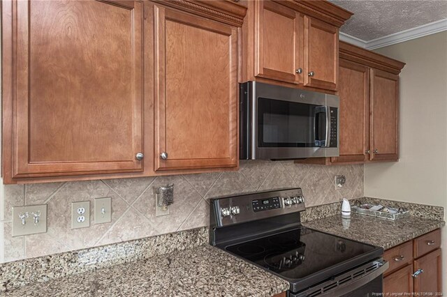 kitchen with dark stone countertops, crown molding, stainless steel appliances, and backsplash