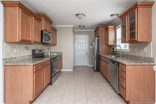 kitchen featuring light tile patterned floors, appliances with stainless steel finishes, light stone countertops, and a sink