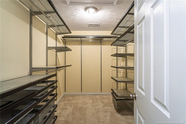 spacious closet with light colored carpet and visible vents