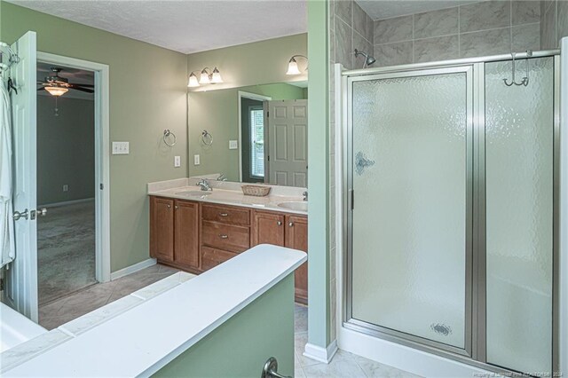 bathroom with ceiling fan, walk in shower, double vanity, a textured ceiling, and tile patterned flooring