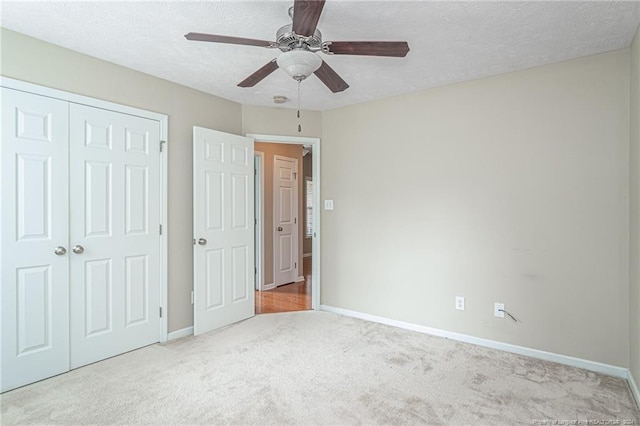 unfurnished bedroom featuring a textured ceiling, carpet, ceiling fan, and a closet