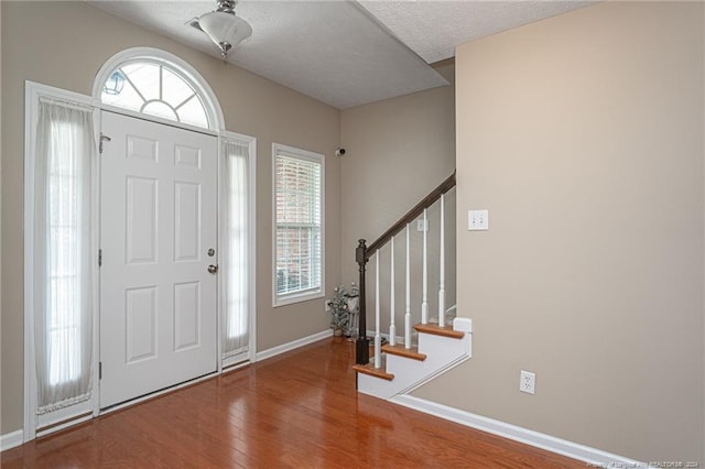 entryway with baseboards, a healthy amount of sunlight, wood finished floors, and stairs