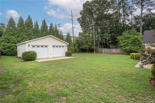 view of yard with an outbuilding, a garage, and fence