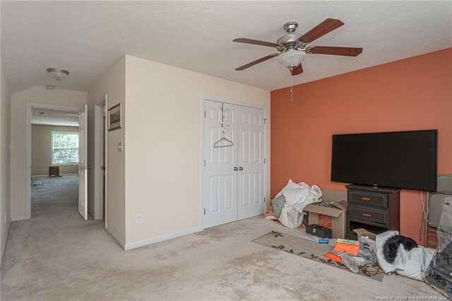 bedroom with a textured ceiling, light carpet, ceiling fan, and a closet