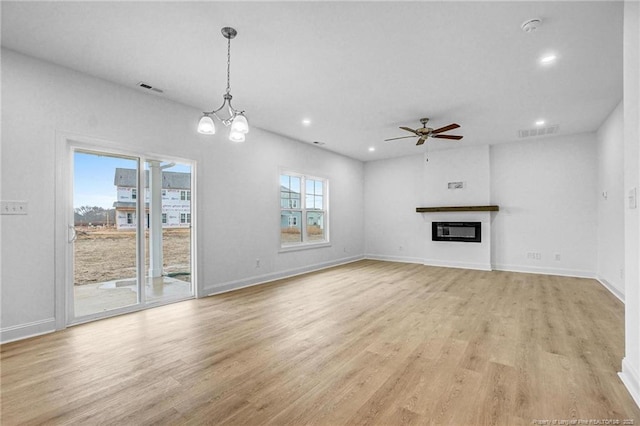 unfurnished living room featuring ceiling fan with notable chandelier and light hardwood / wood-style floors