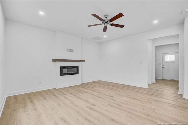 unfurnished living room featuring ceiling fan, heating unit, and light wood-type flooring