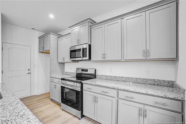 kitchen featuring light stone countertops, stainless steel appliances, and light hardwood / wood-style floors