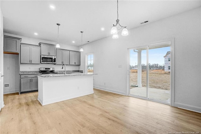 kitchen featuring gray cabinets, an island with sink, appliances with stainless steel finishes, and pendant lighting