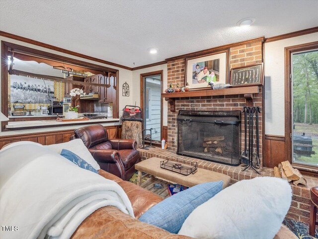 living room with brick wall, a textured ceiling, a brick fireplace, and hardwood / wood-style floors