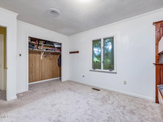 unfurnished bedroom with ornamental molding, light colored carpet, a closet, and a textured ceiling