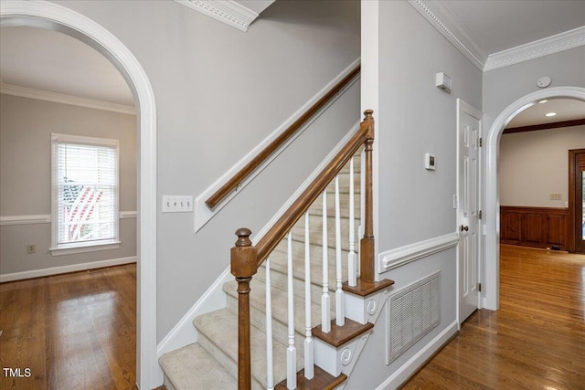 stairway with wood-type flooring and ornamental molding