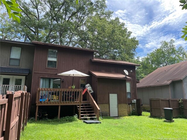 rear view of property with fence, a deck, and a yard