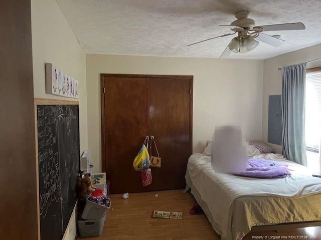 bedroom with ceiling fan, a textured ceiling, and wood finished floors