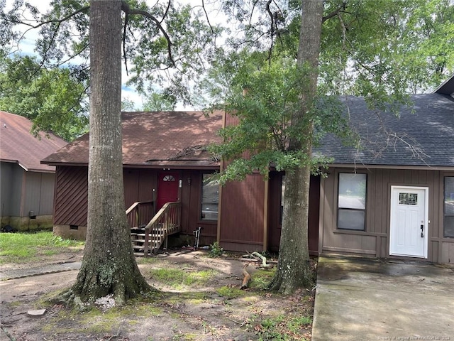 view of front facade with a shingled roof and crawl space