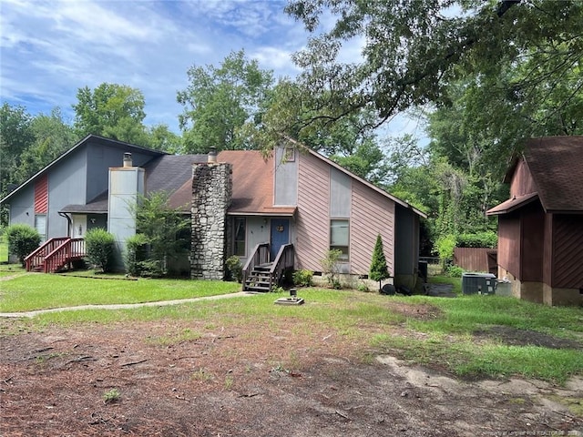 exterior space with cooling unit, a yard, and a chimney