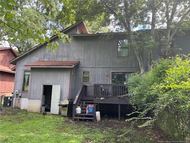 rear view of property featuring central AC, a lawn, and a deck