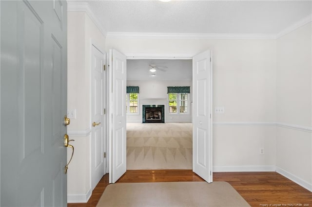 foyer featuring a fireplace, a ceiling fan, crown molding, and wood finished floors