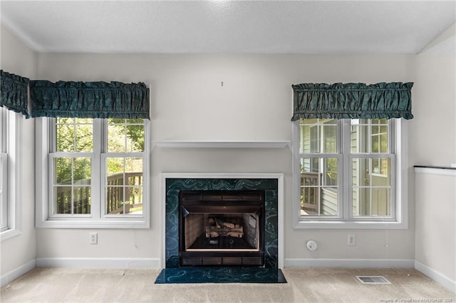 unfurnished living room featuring visible vents, carpet floors, baseboards, and a premium fireplace