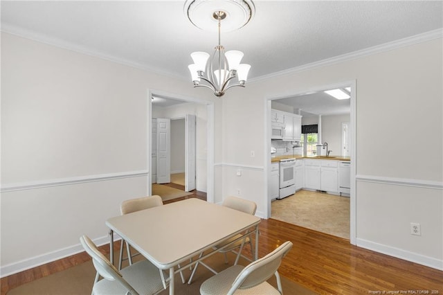 dining space with ornamental molding, baseboards, a notable chandelier, and wood finished floors